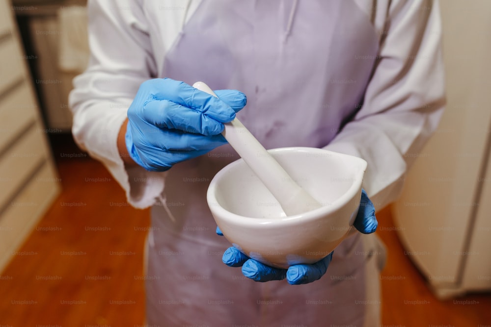a person in blue gloves holding a white bowl
