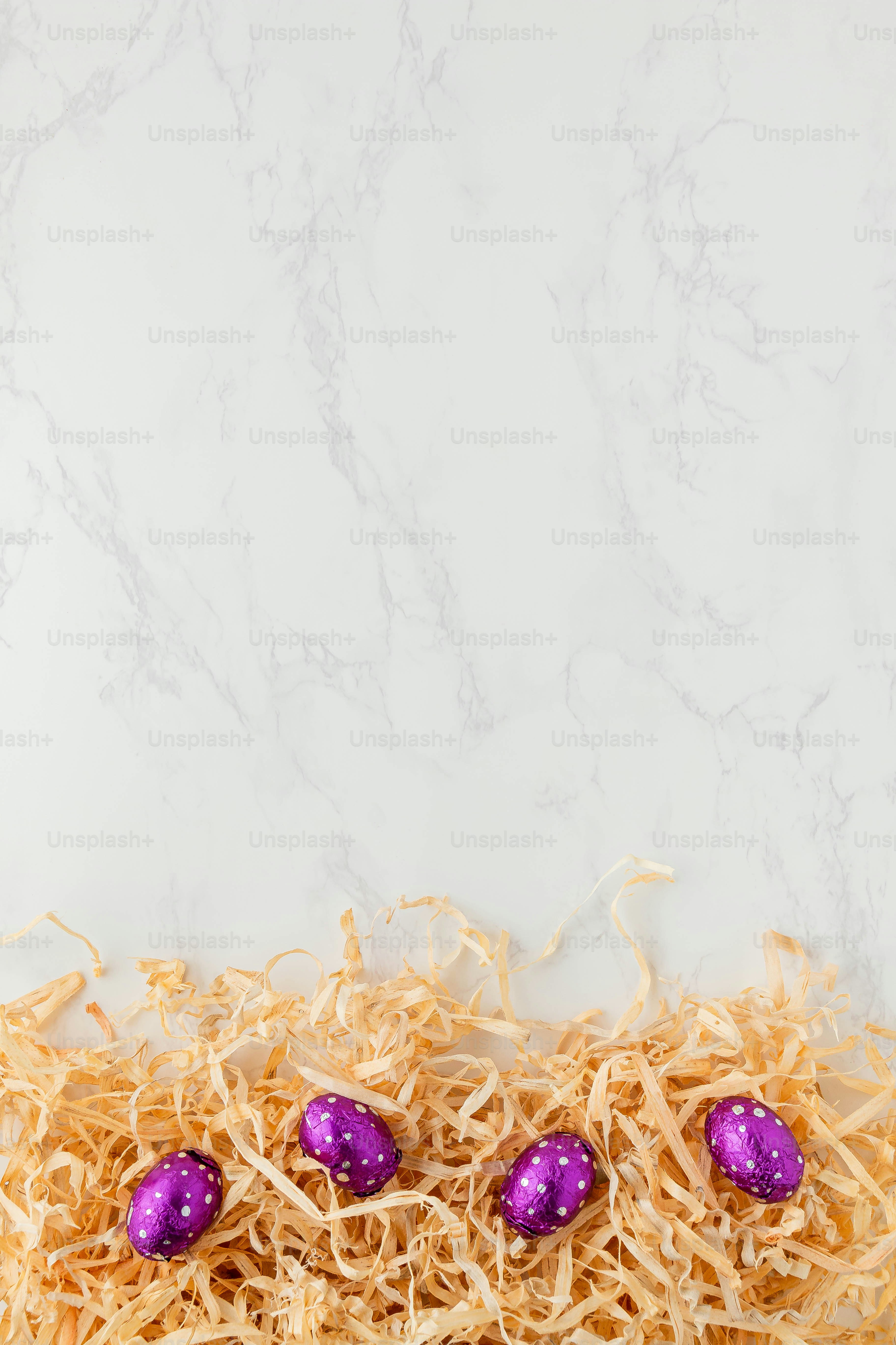 ein Haufen Stroh mit drei lila Eiern darin