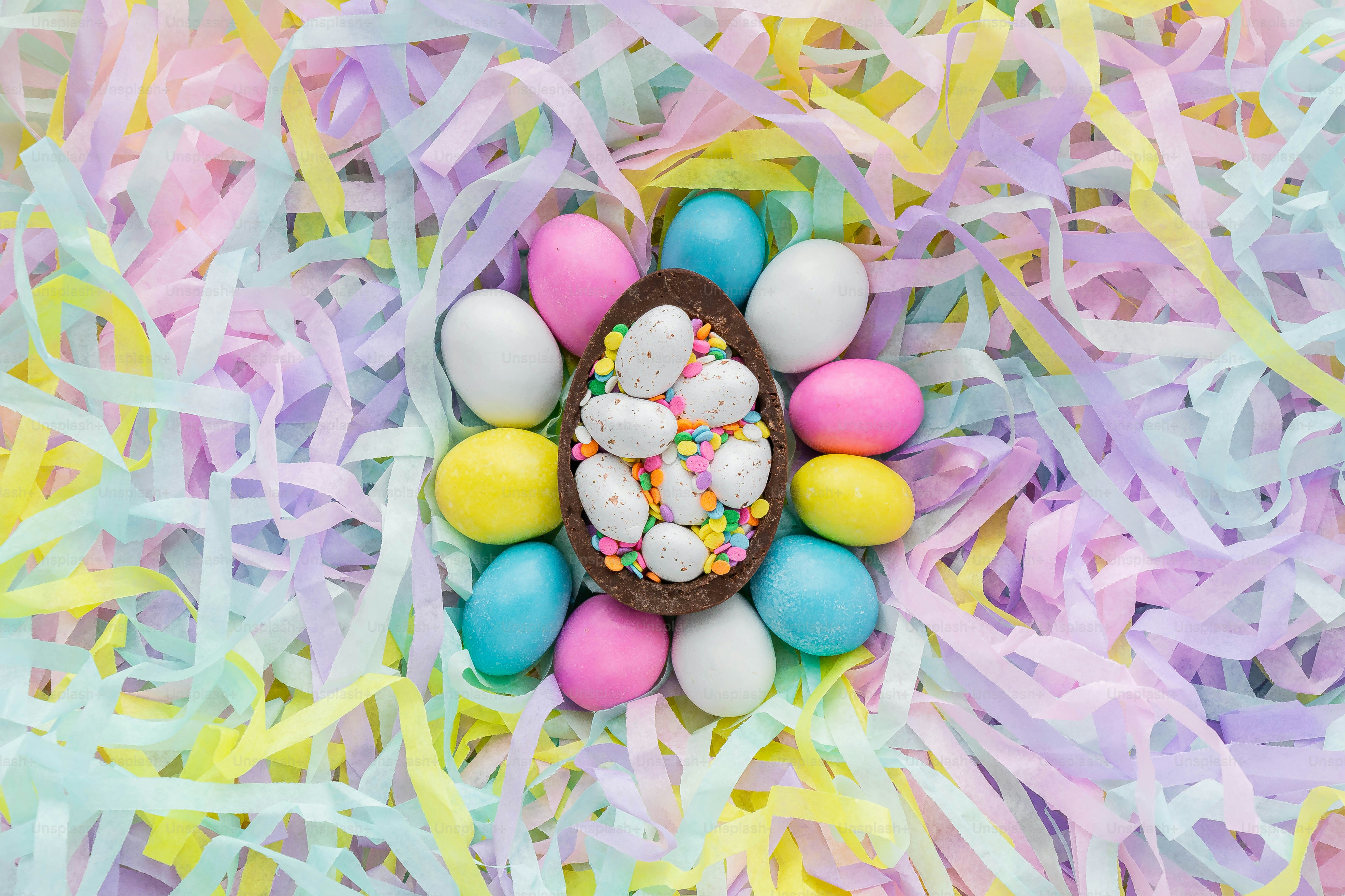 Ein Blick von oben auf ein Schokoladen-Osterei, umgeben von bunten Luftschlangen