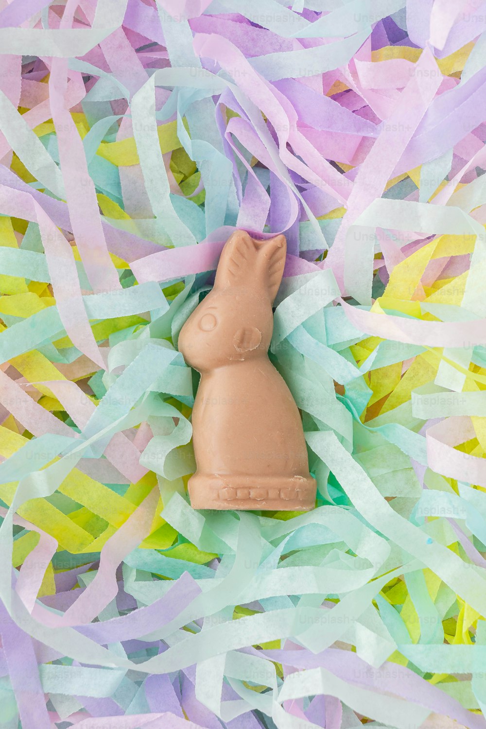a chocolate bunny sitting on top of a pile of streamers