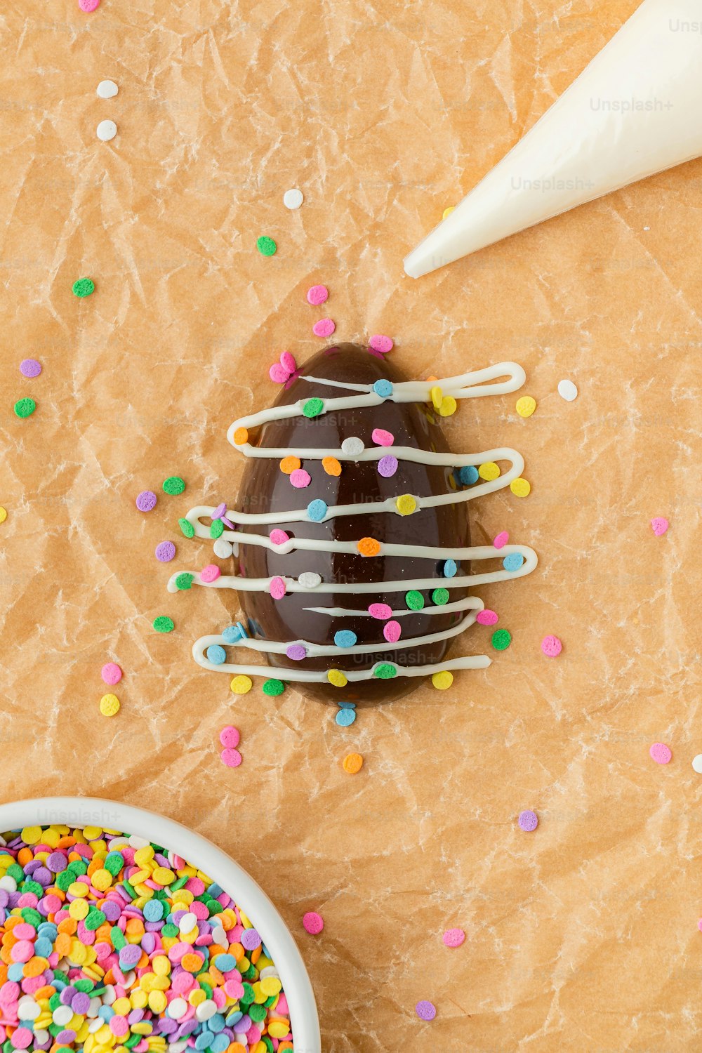 a chocolate donut with sprinkles and a bowl of sprinkle