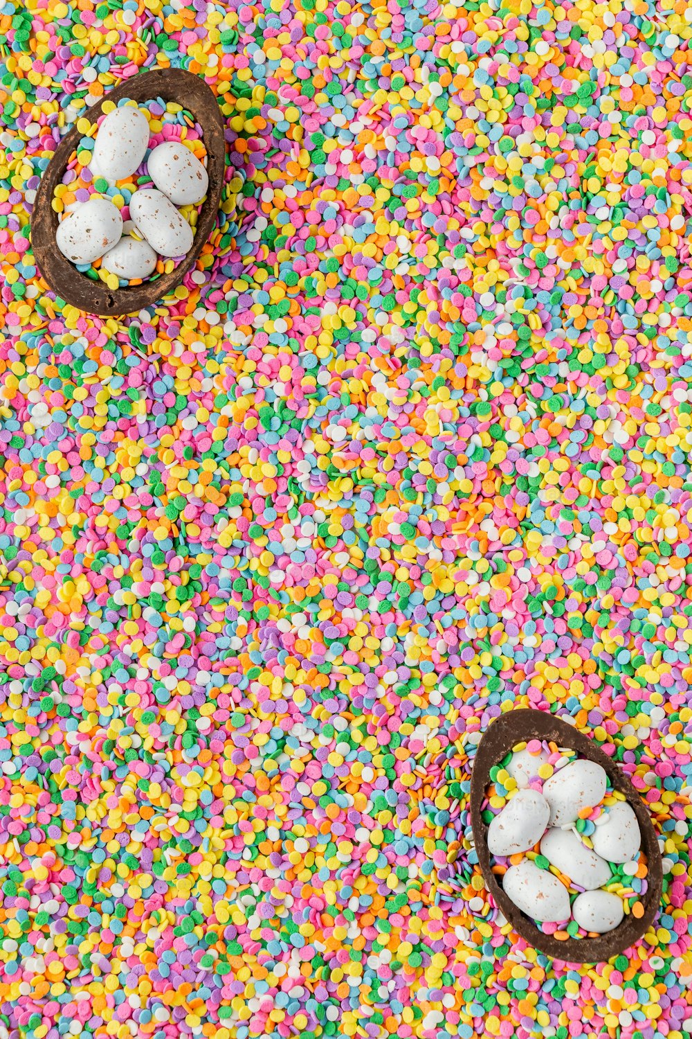 two baskets filled with small white eggs surrounded by sprinkles