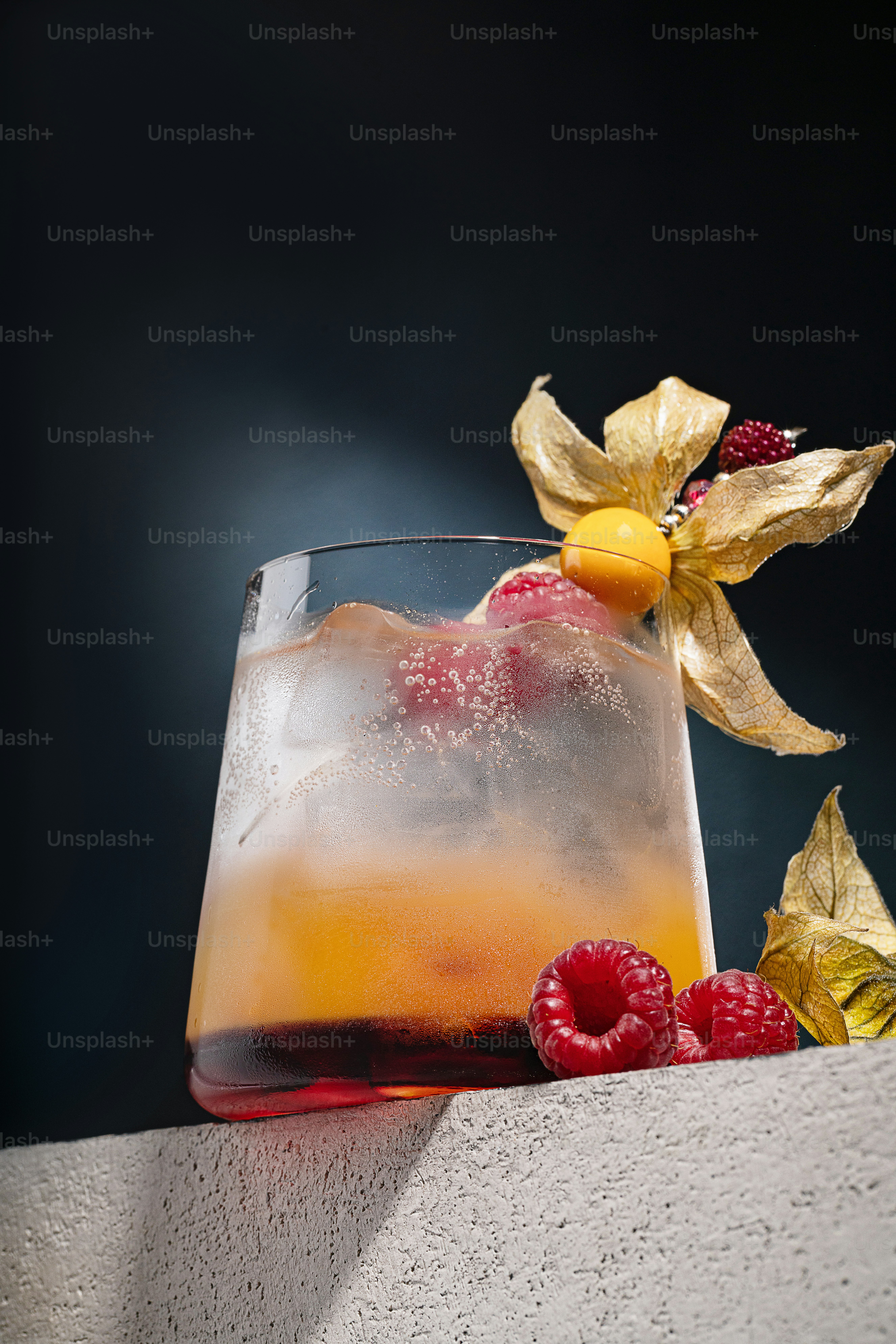 a glass filled with ice and raspberries on top of a table