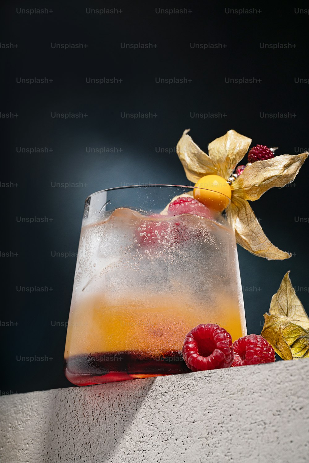 a glass filled with ice and raspberries on top of a table