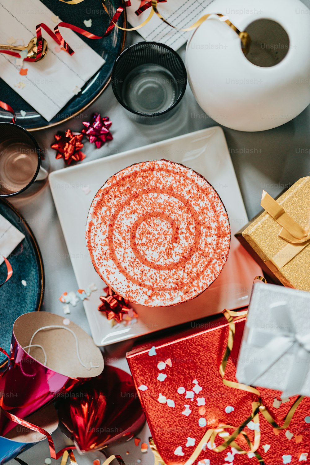 a white plate topped with a red cake next to presents