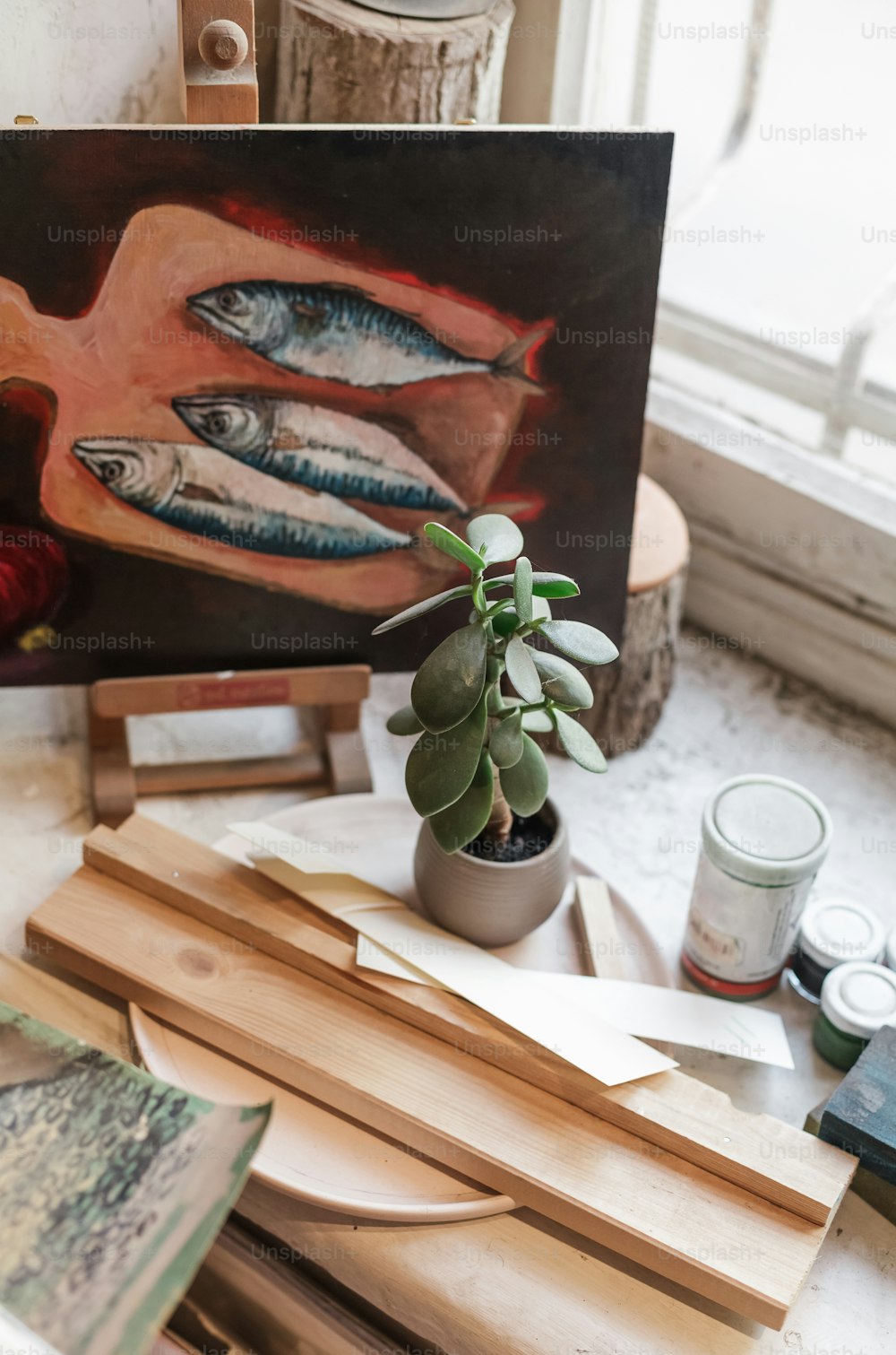 Una pintura de pescado en una mesa junto a una planta en maceta