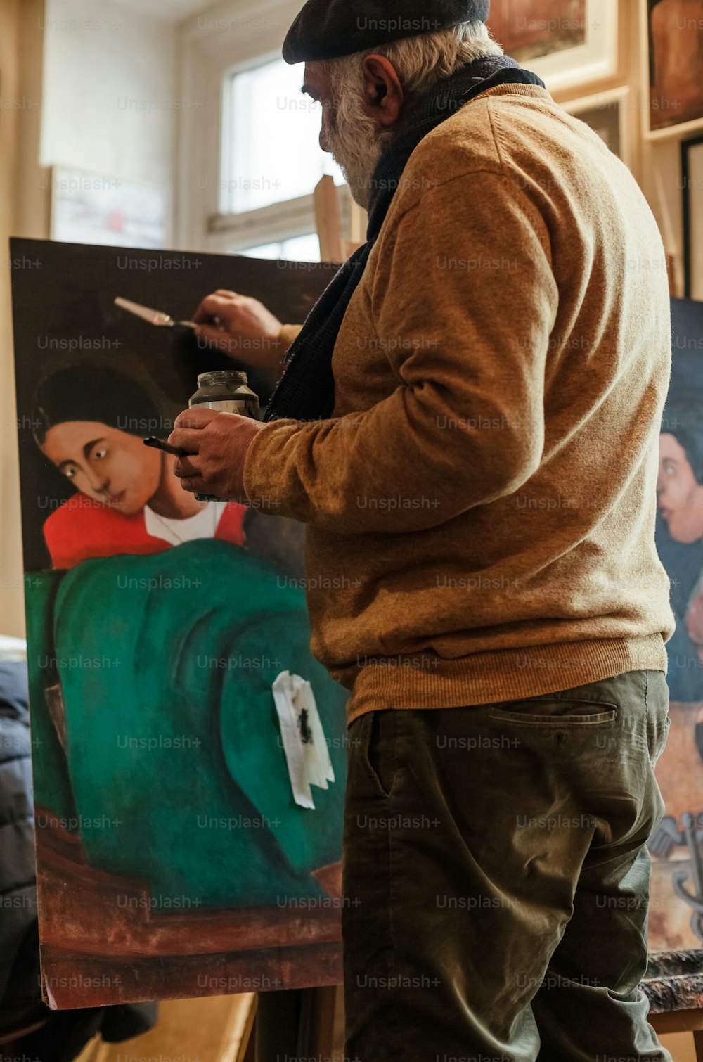 a man standing in front of a painting holding a brush