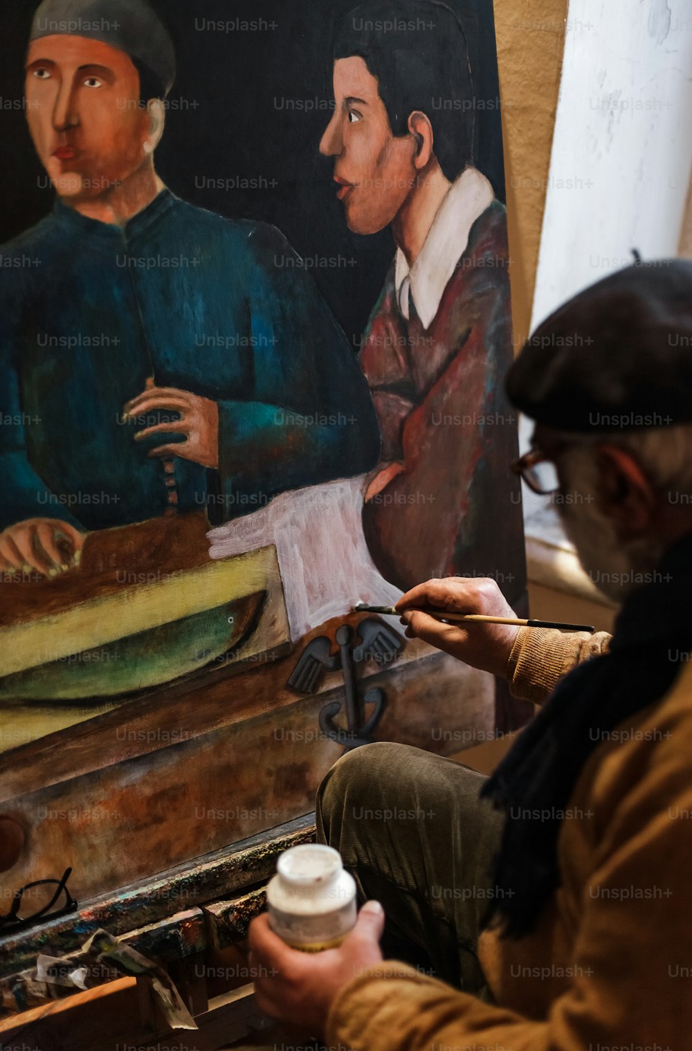um homem sentado na frente de uma pintura de dois homens