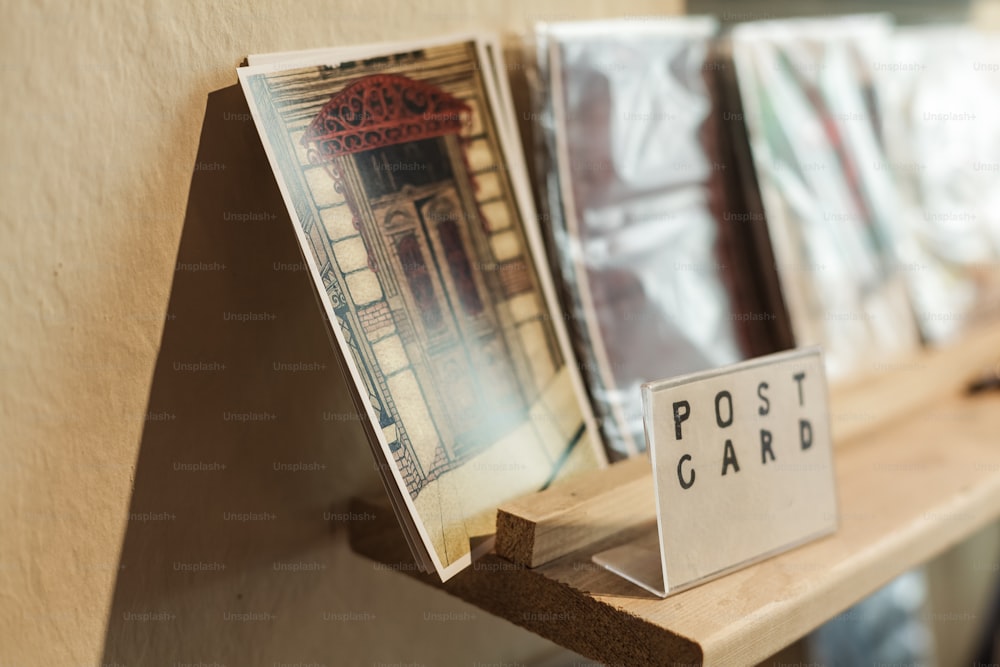 Una fila de postales sentadas encima de un estante de madera
