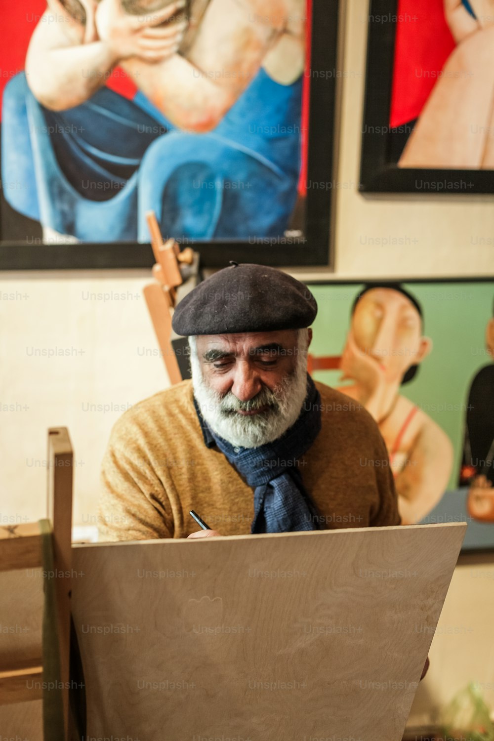 a man sitting at a table working on a piece of wood