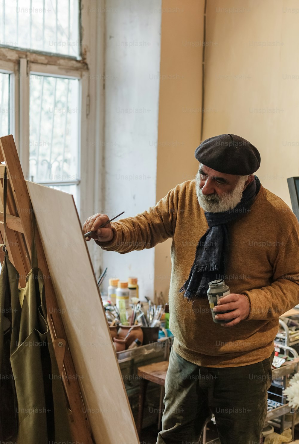 a man with a beard is painting on a easel