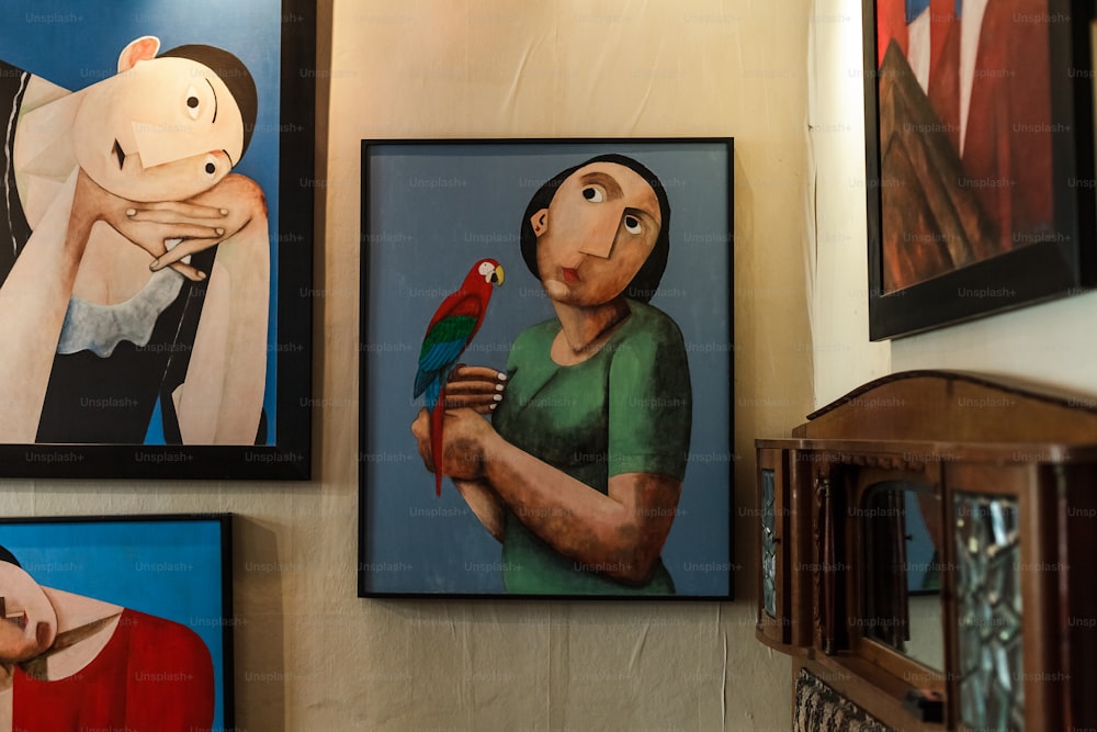 a painting of a woman holding a parrot next to a painting of a woman holding