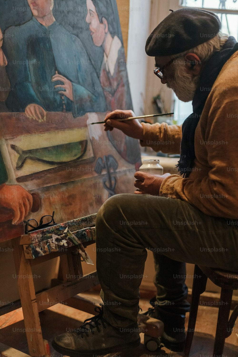 um homem sentado em uma cadeira na frente de uma pintura