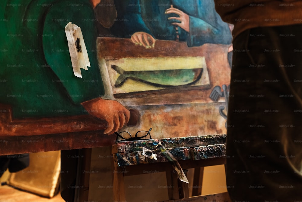 um homem de pé ao lado de uma pintura em um cavalete