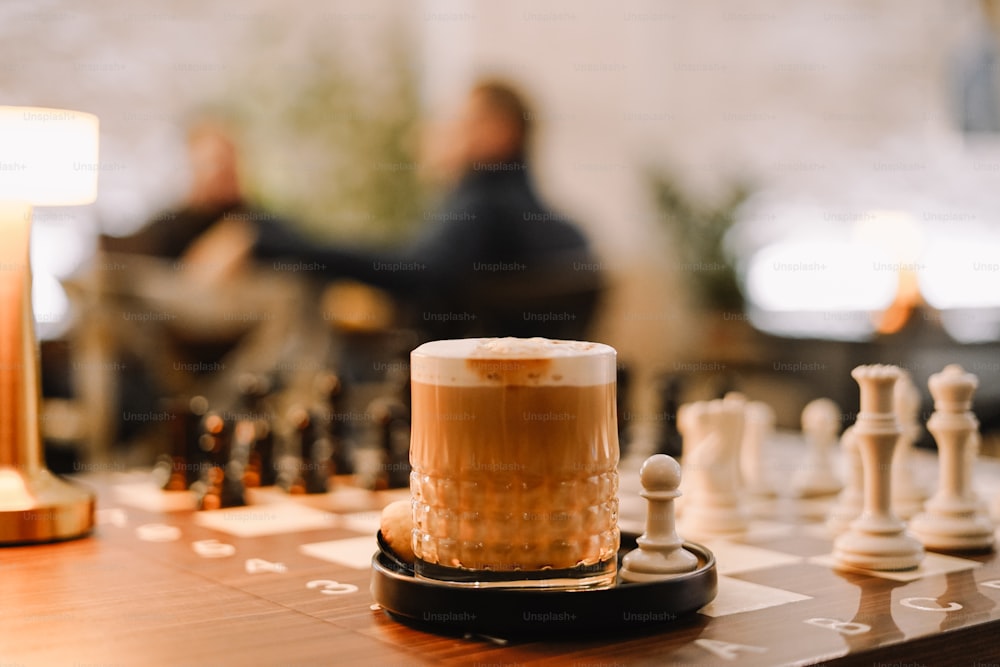 a glass of beer sitting on top of a chess board