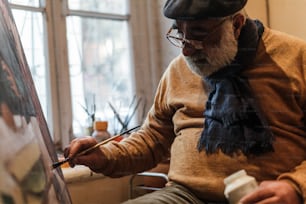 an older man is painting on a canvas