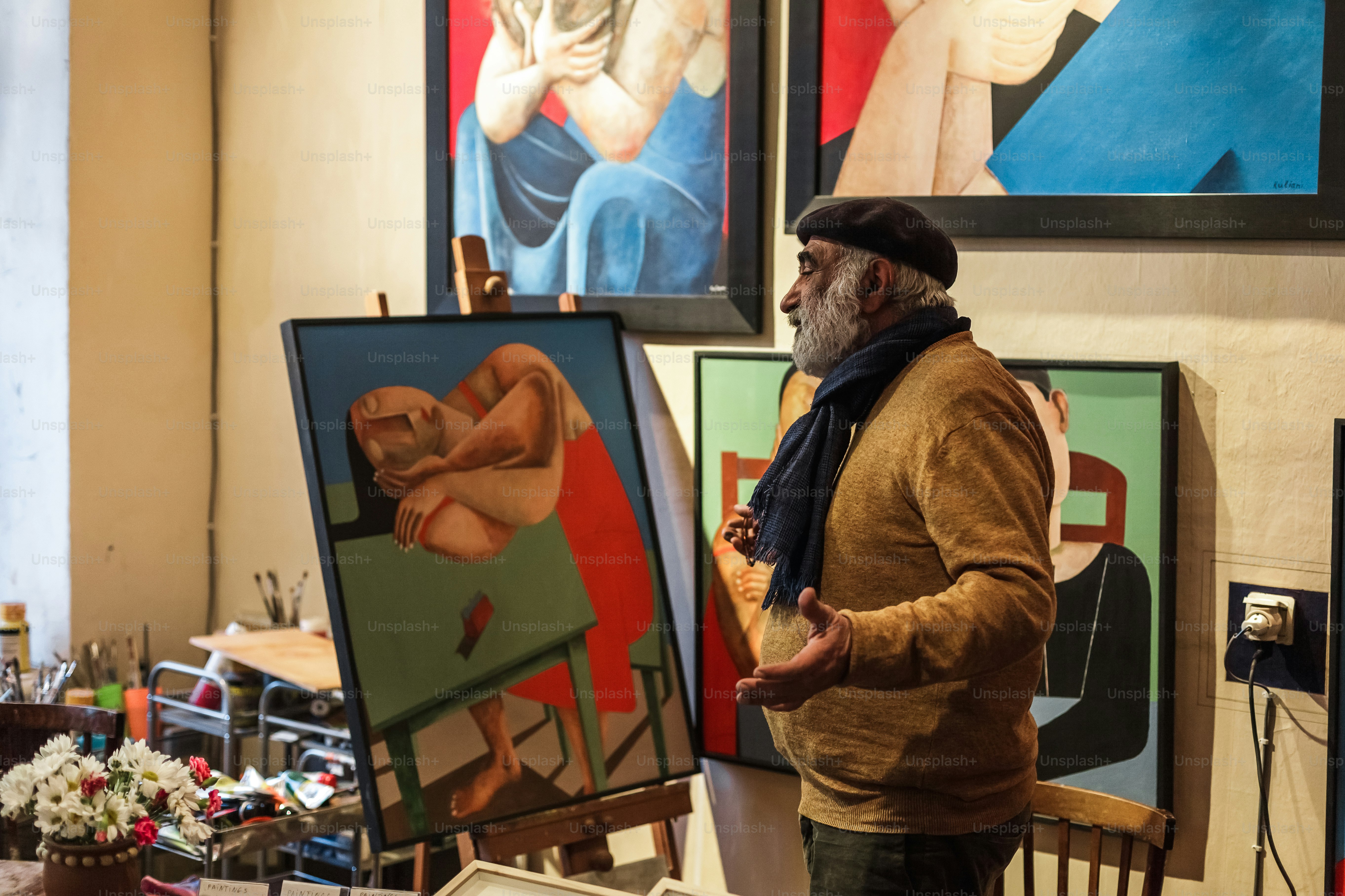 a man standing in front of paintings in a room