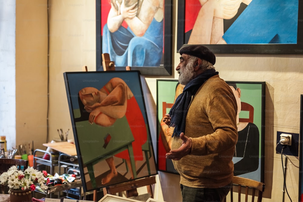 Un homme debout devant des peintures dans une pièce