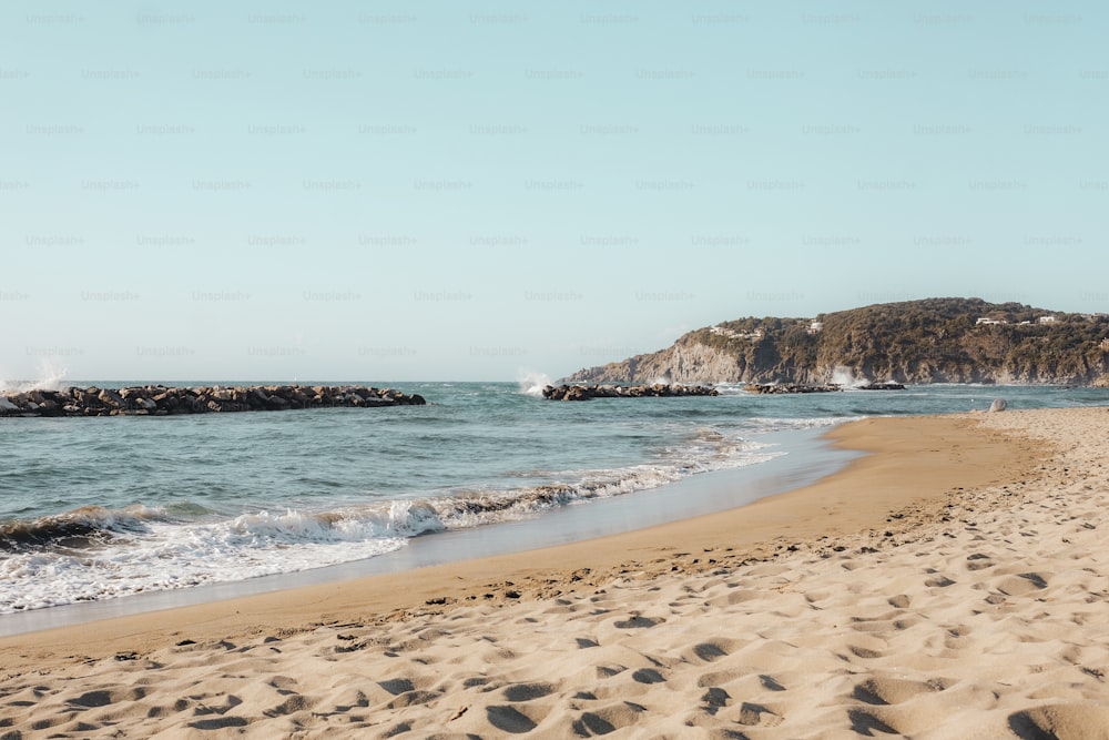 a sandy beach with waves coming in to shore