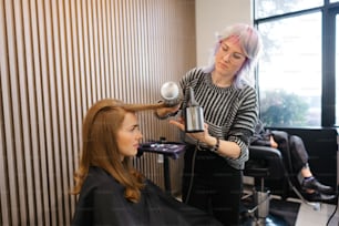 a woman getting her hair styled by a hair stylist