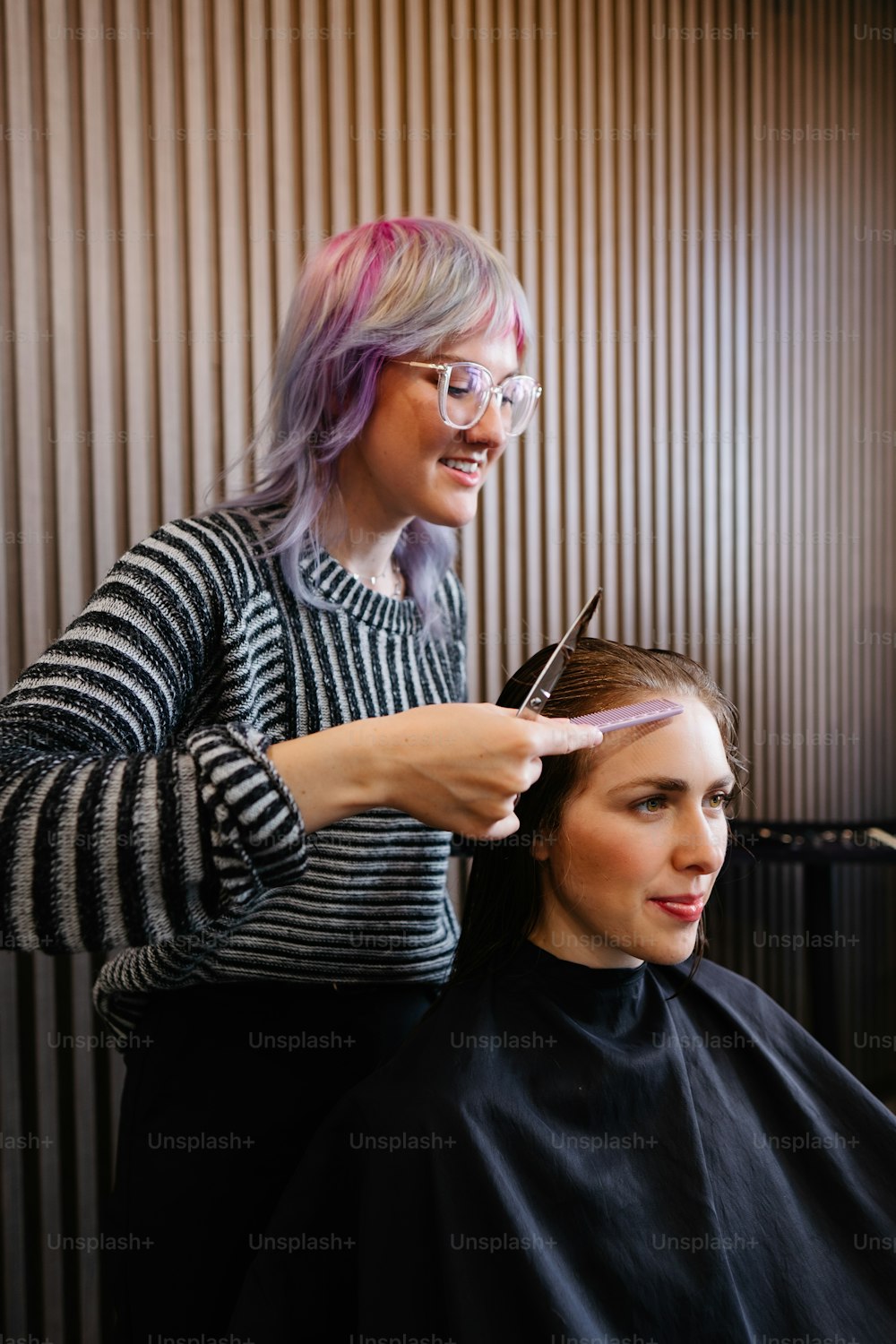 a woman cutting another woman's hair with a pair of scissors