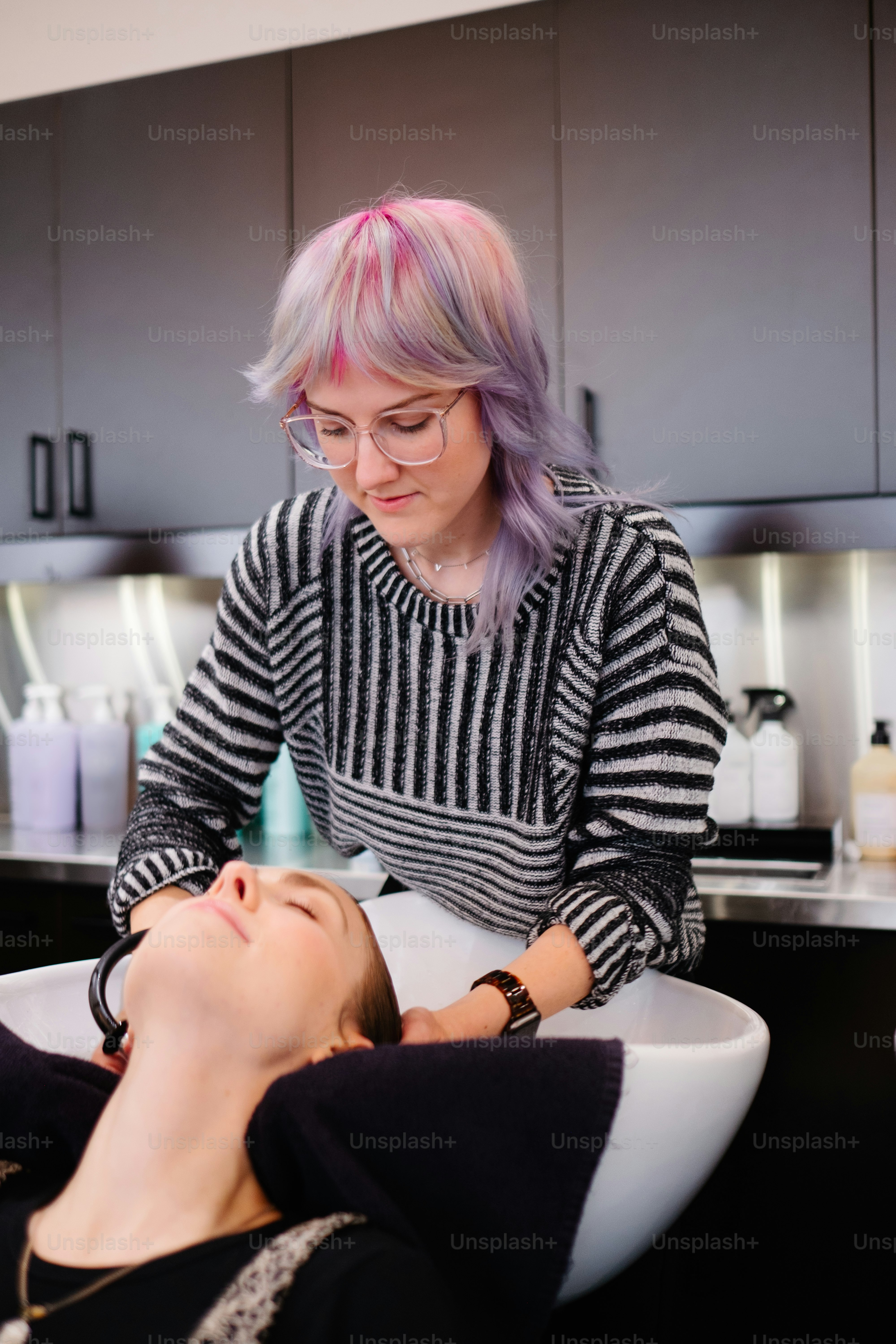 A woman sitting in a chair getting her hair cut photo – Professional ...