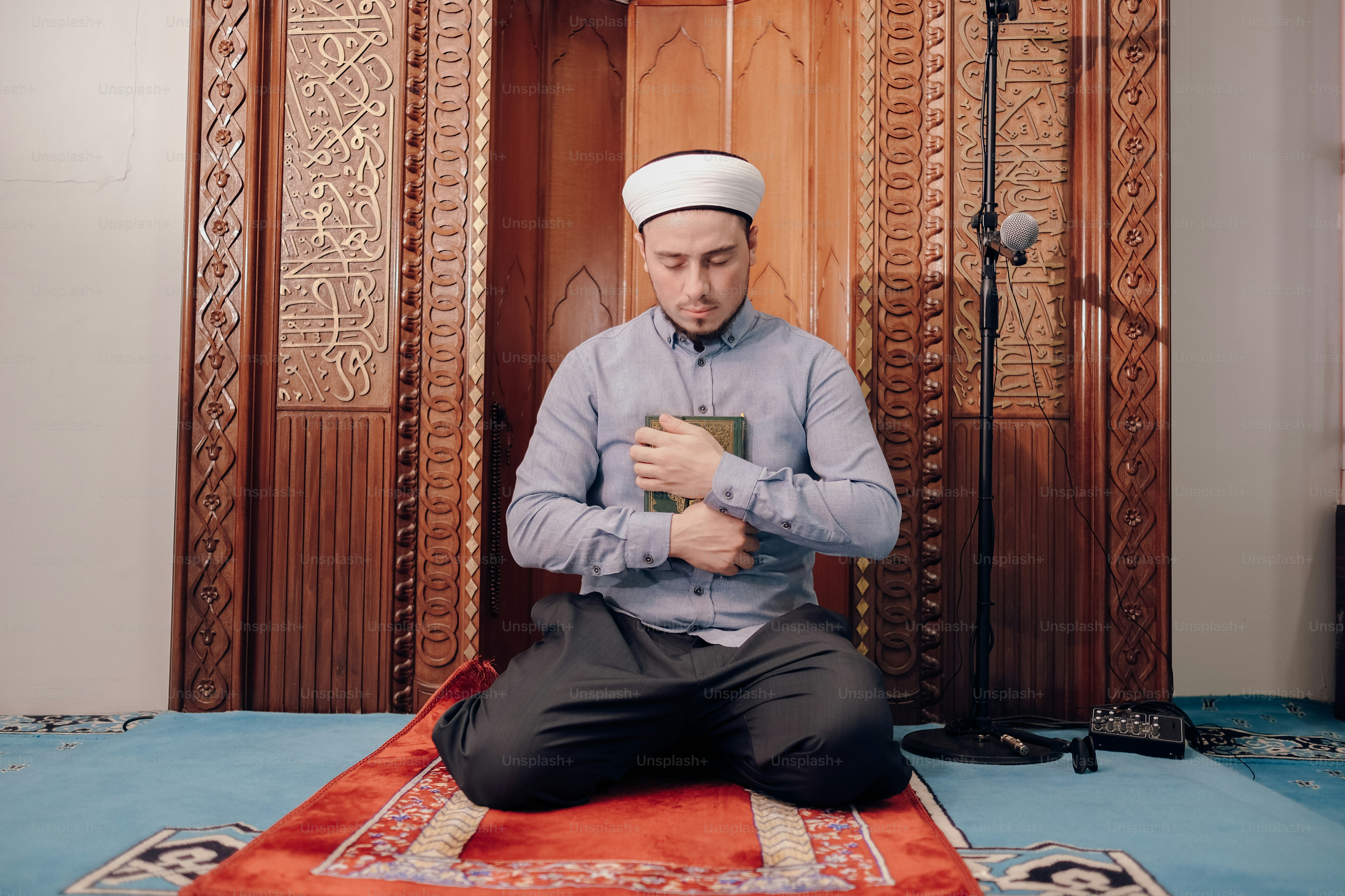 seorang pria duduk di atas karpet sambil memegang buku
