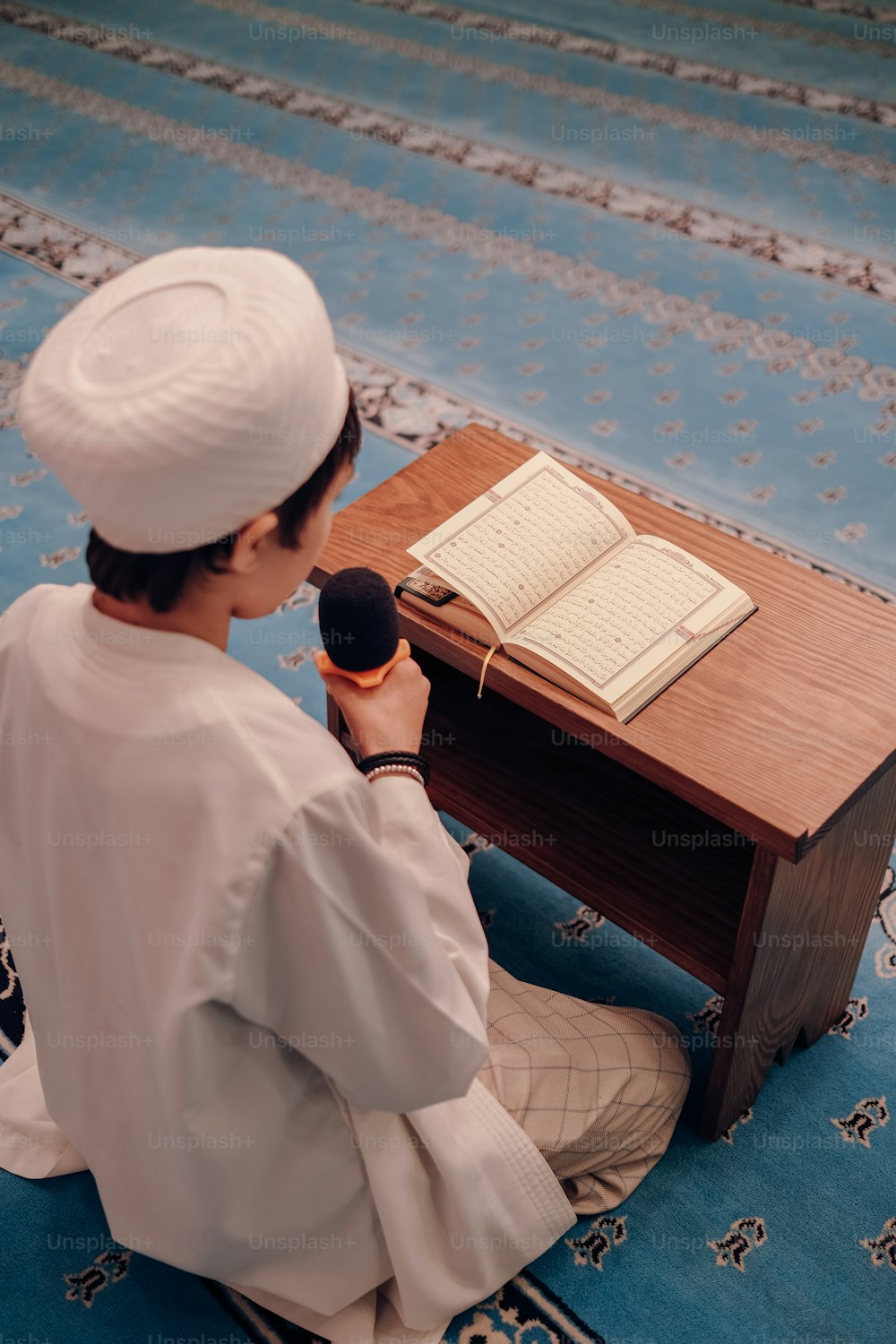 une personne assise sur un tapis tenant un microphone