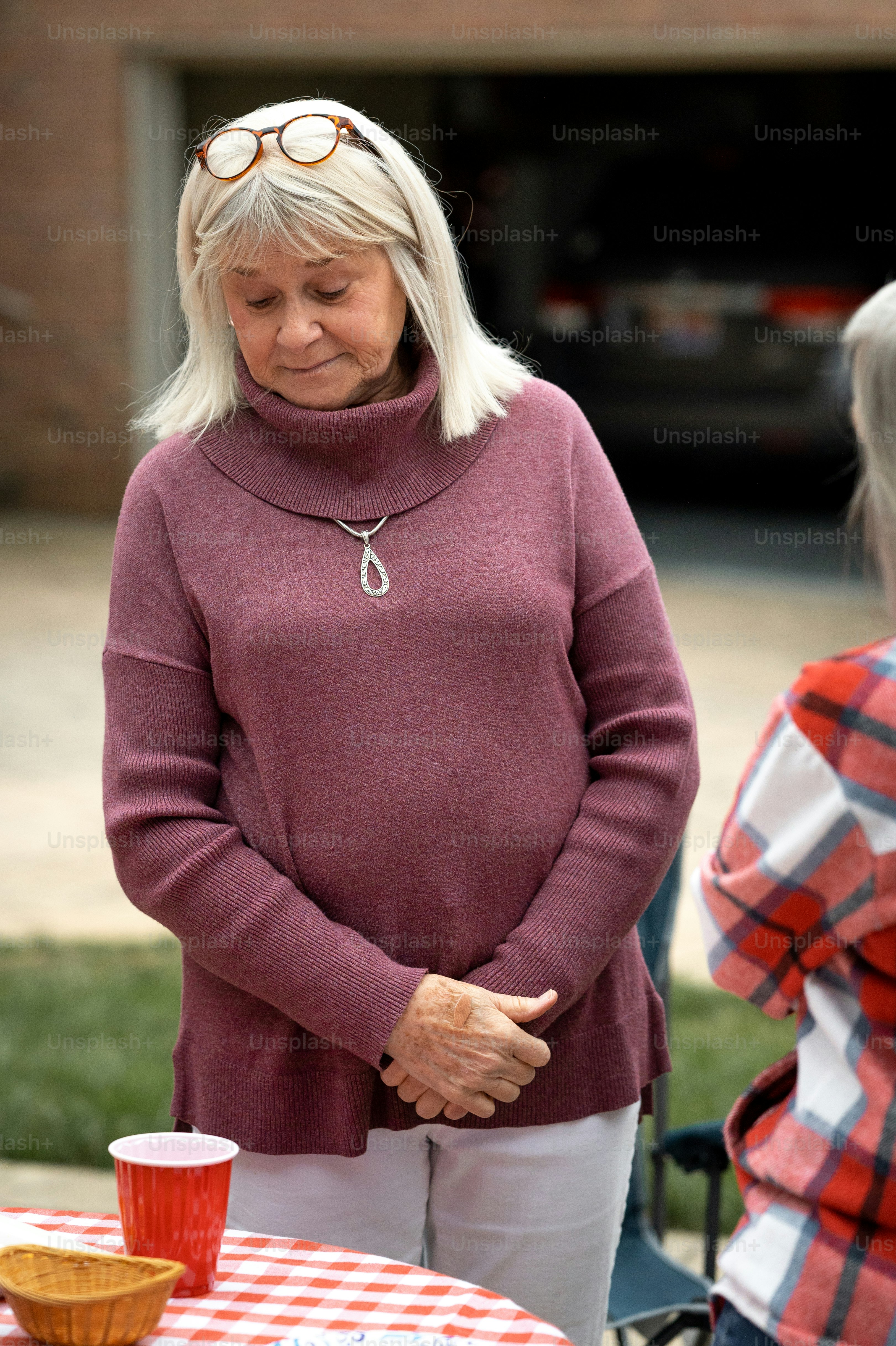 une femme debout à côté d’une table avec une nappe à carreaux rouge et blanc