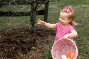 a little girl in a pink dress holding a basket of eggs