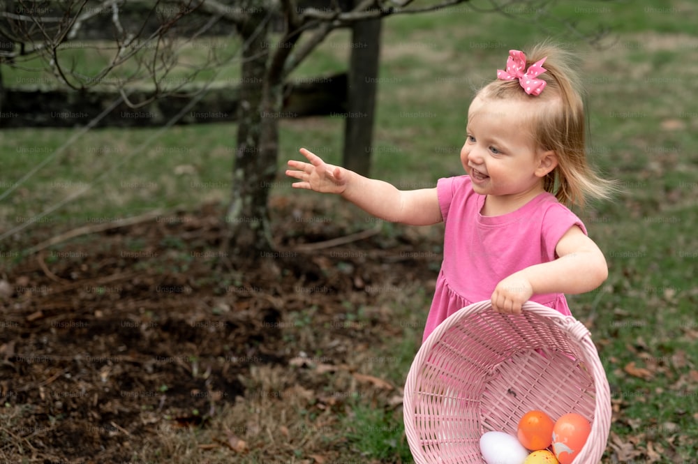 a little girl in a pink dress holding a basket of eggs