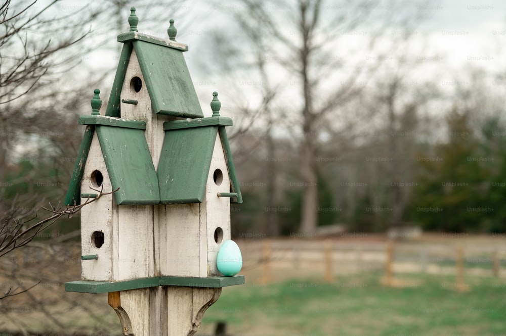 a bird house with a green roof and two blue eggs