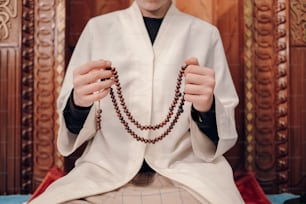 Ein Mann in Priesterkleidung hält einen Rosenkranz