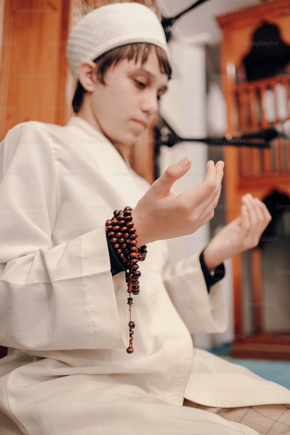 a young boy wearing a white outfit and a beaded bracelet