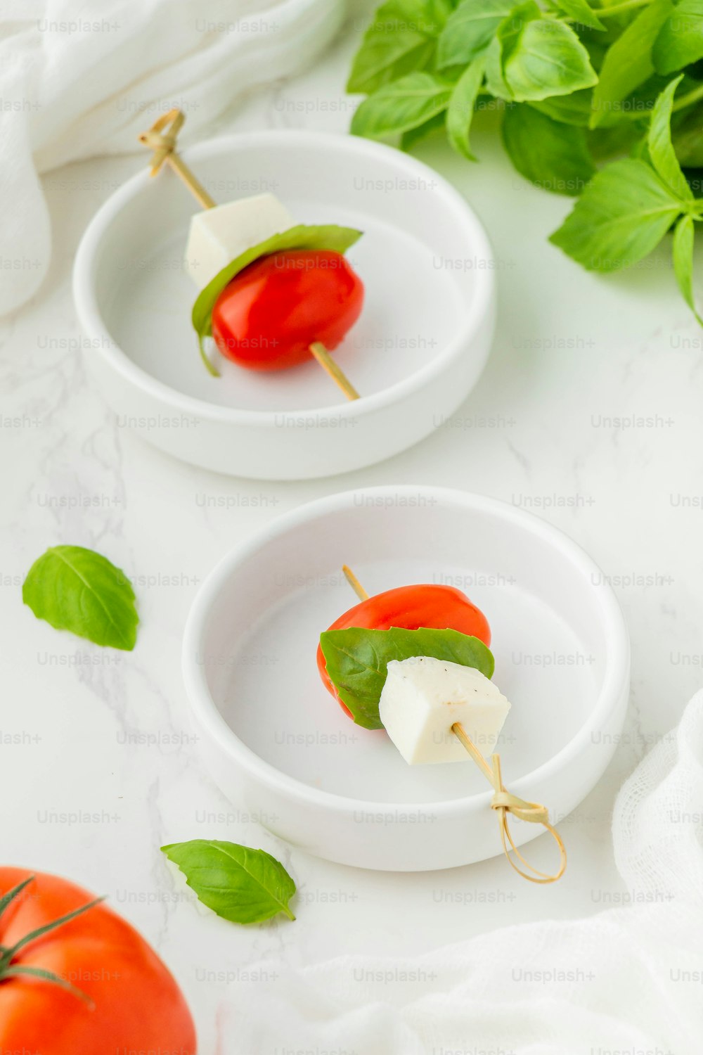 two small white bowls filled with cheese and tomatoes