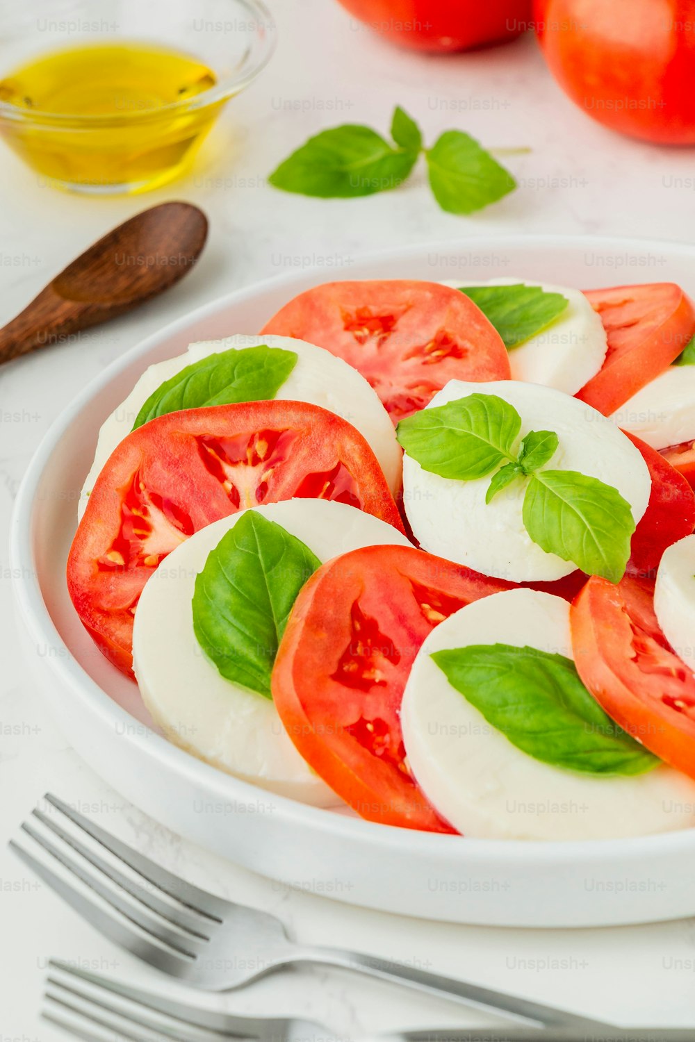 a white bowl filled with sliced tomatoes and basil