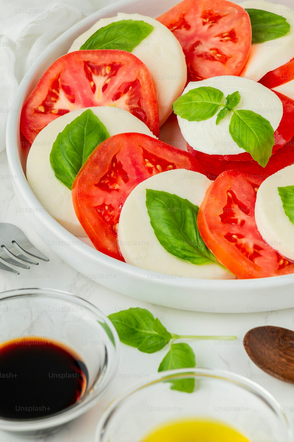 un plato de tomates en rodajas con albahaca y aceite de oliva