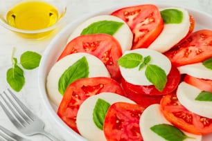 a white bowl filled with sliced tomatoes and basil