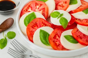 uma tigela branca recheada com tomates fatiados e manjericão