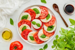 un bol blanc rempli de tomates tranchées et de basilic