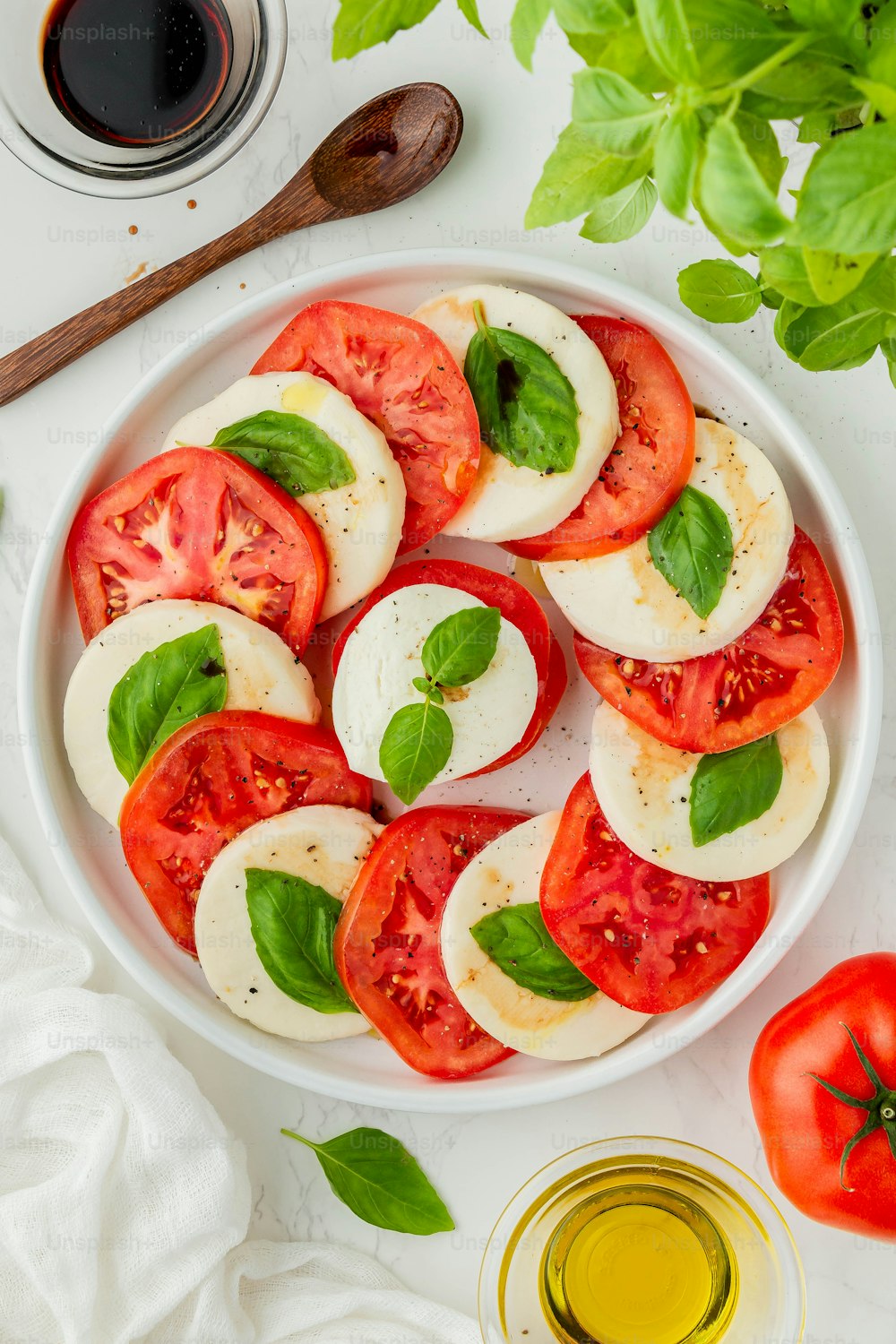 un bol blanc rempli de tomates tranchées et de basilic