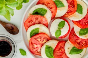 a plate of sliced tomatoes and basil on a table