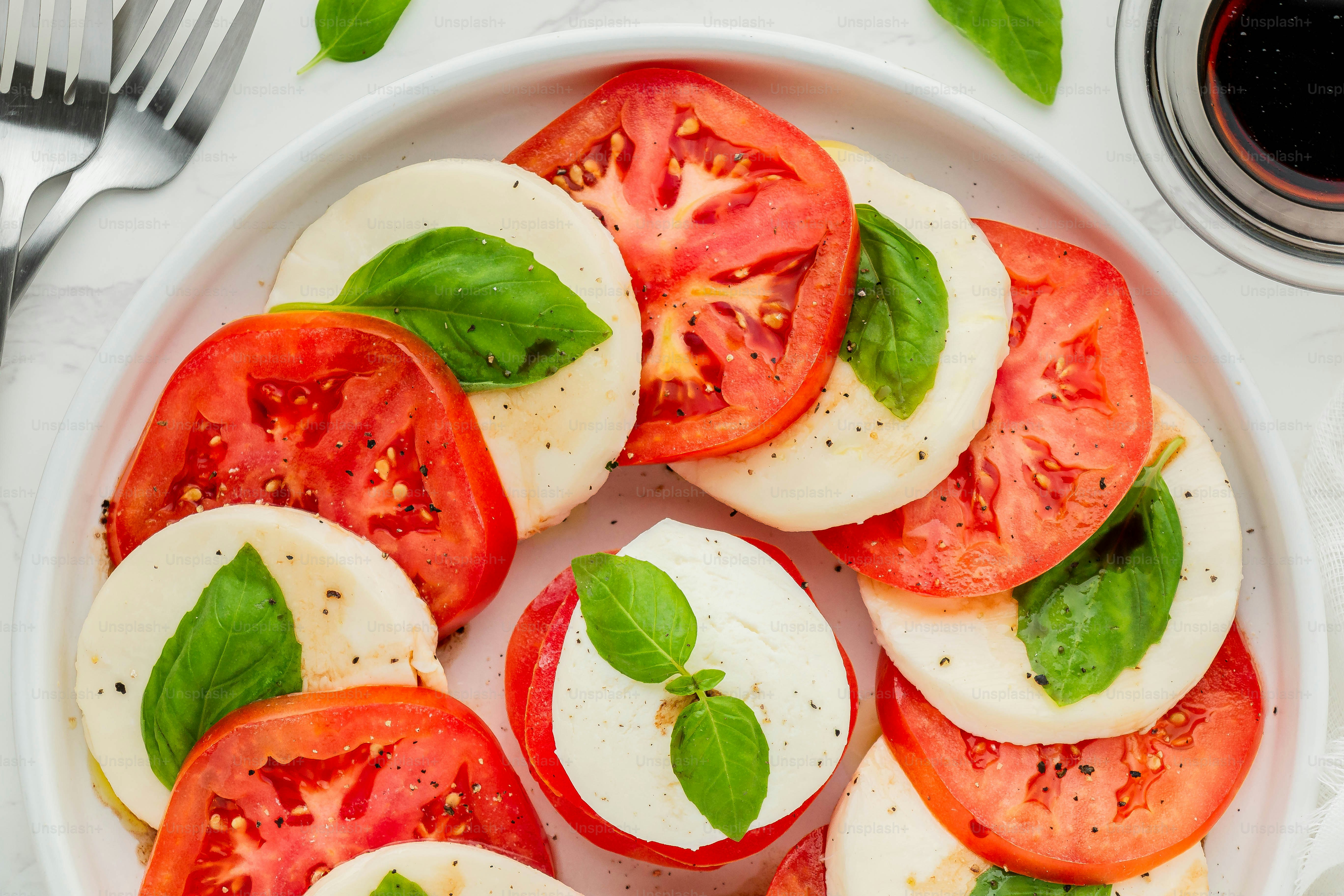 a white plate topped with sliced tomatoes and basil