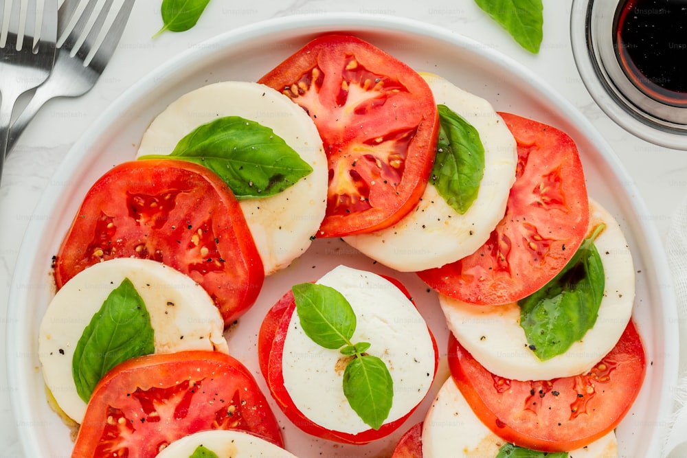 a white plate topped with sliced tomatoes and basil