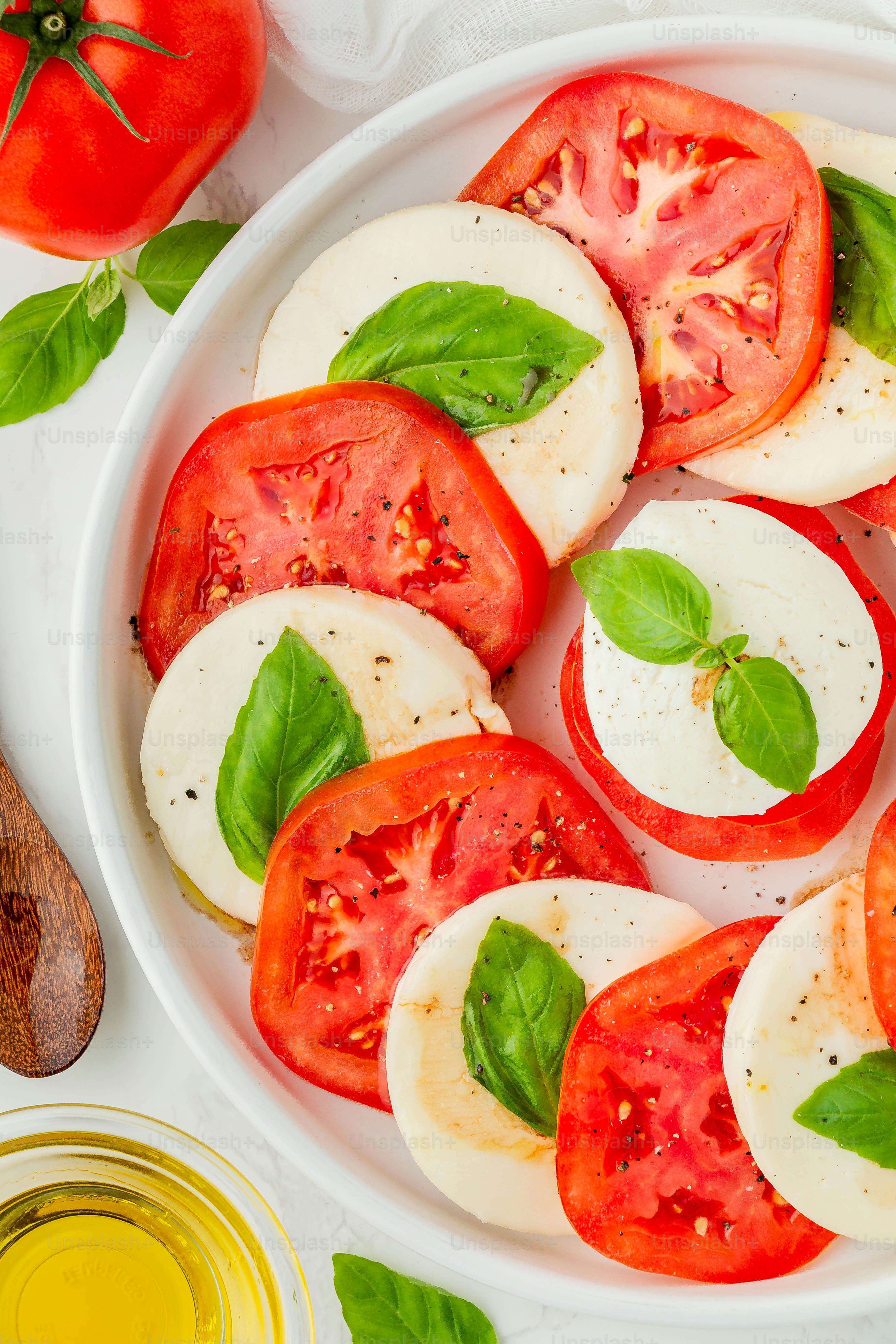 a white plate topped with sliced tomatoes and basil