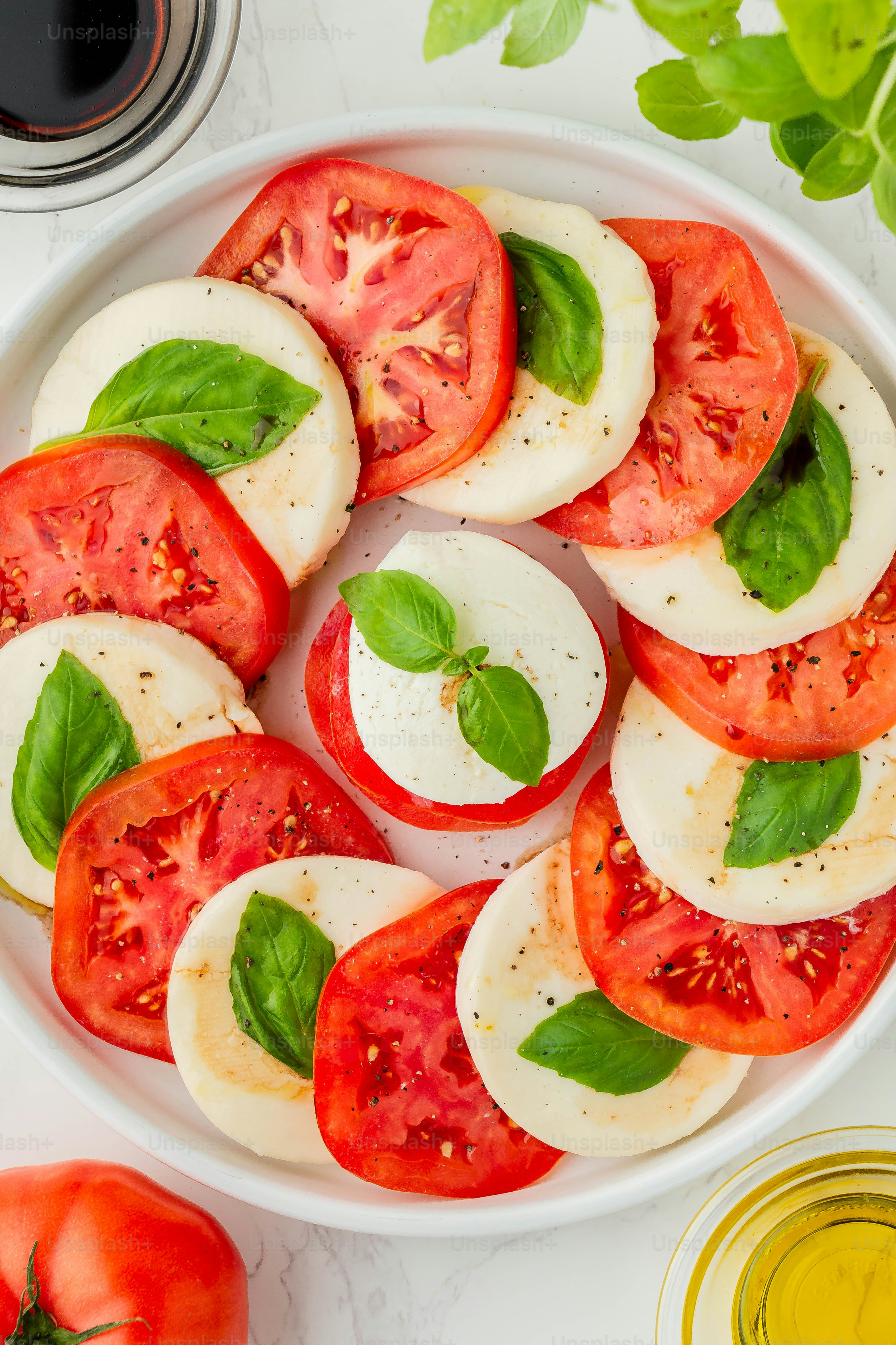 a white plate topped with sliced tomatoes and basil