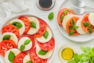 um prato branco coberto com tomates fatiados e manjericão