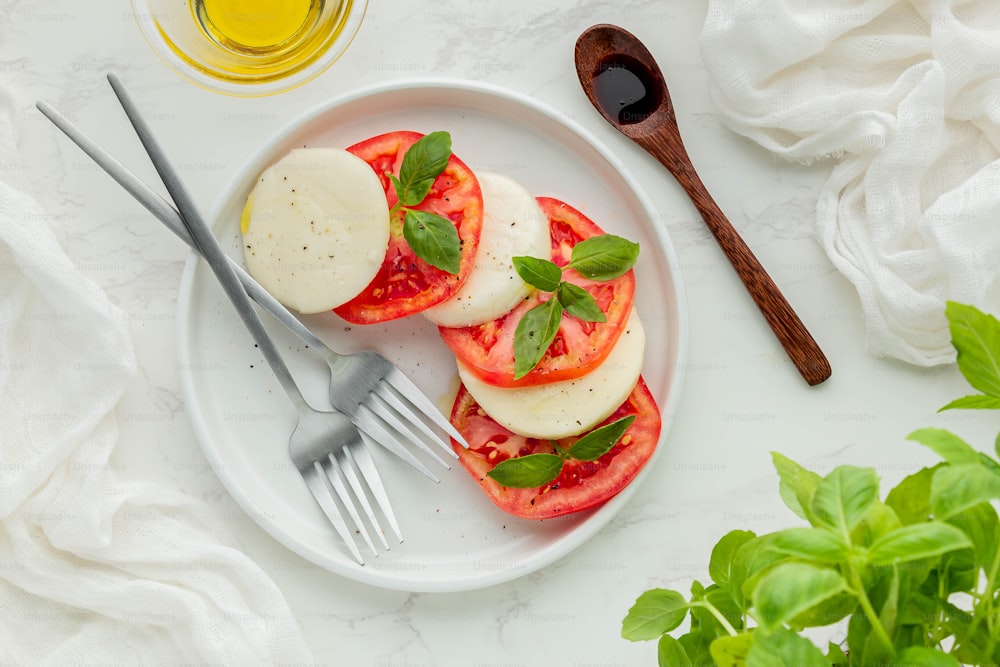 un plato blanco cubierto con tomates en rodajas y queso