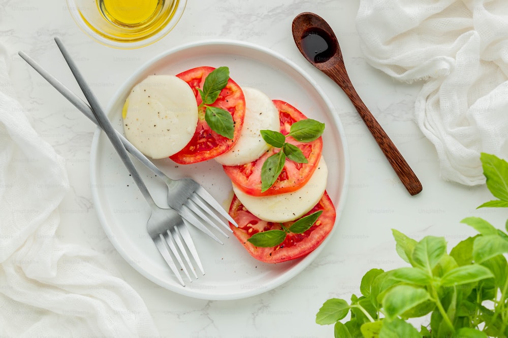 a white plate topped with sliced tomatoes and cheese