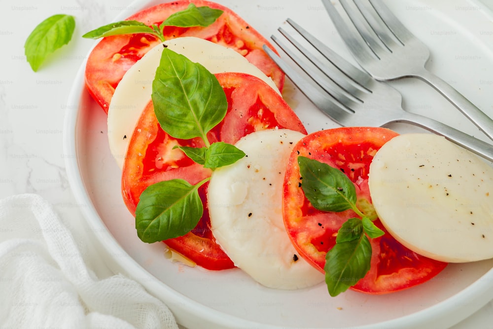 a white plate topped with sliced tomatoes and mozzarella